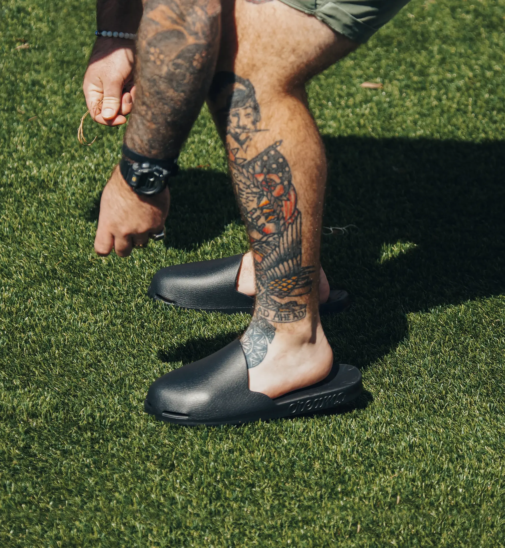 Black Creams closed-toe slides worn on turf