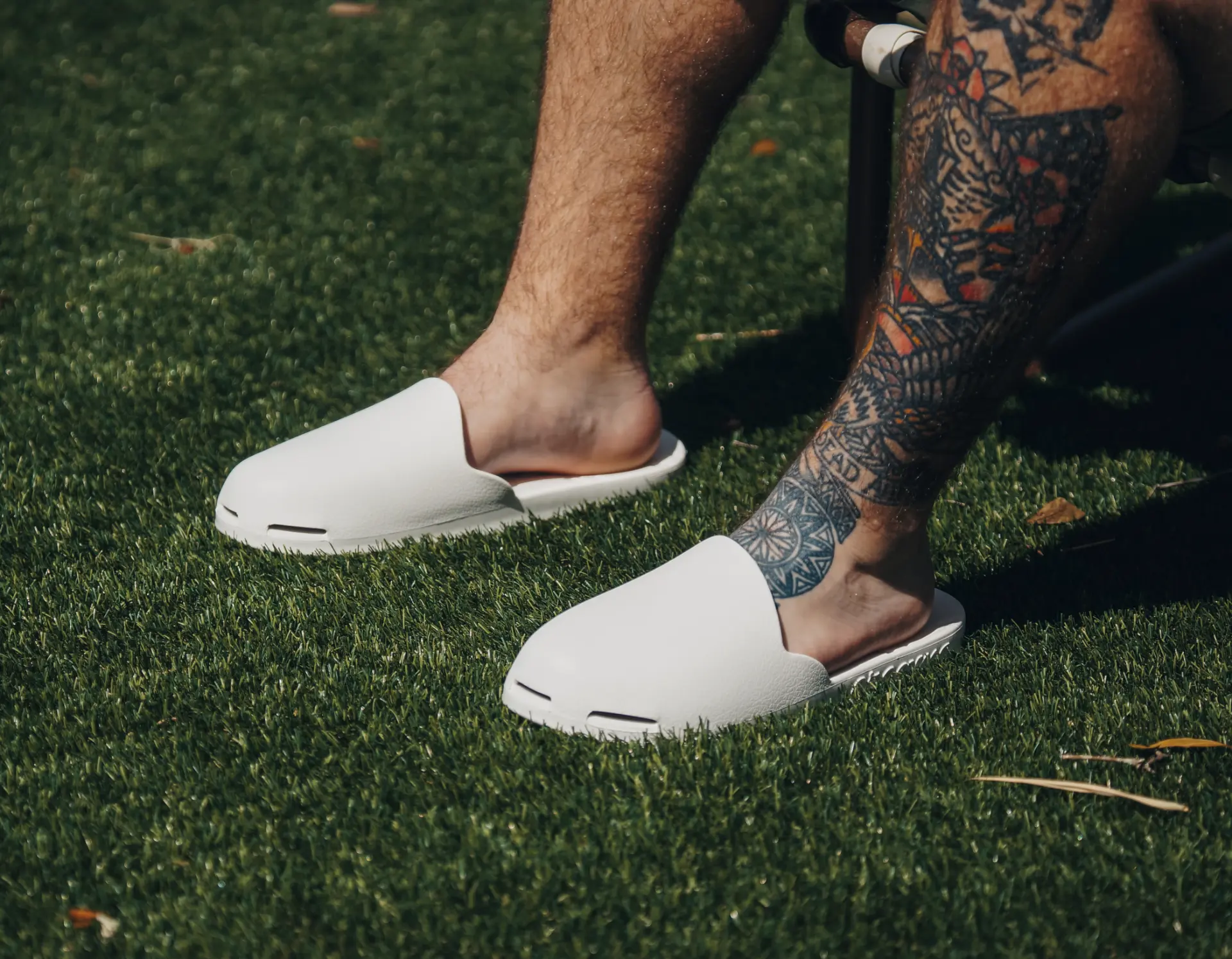 White Creams closed-toe slides worn on turf